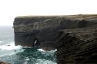 To the left the central sandy portion of the cliff represents the cross-bedded Tullig Formation sands, and silts. The channeling and sorting of the quartz rich character of the sands on delta front reflect waves impinging on the delta front sands that filled distributary channels and/or proximal bar sands (Andy Pulham personal communication and Martinsen et al., 2008). The upper portion of cliff is composed of sand stringers and shales of a marine bay within wave base. The lower portion of the cliff represents silts, shales and some thin sands the accumulated in water that deepens down section to below wave base. A delta mouth gulley lies just below the central sandstone unit. To the right are rythmic alternations of silts and mud of distal delta plumes that shallow up to a climbing ripple facies probably within wave base. This cliff represents approximately 50m of section of Upper Carboniferous or Namurian sediments.